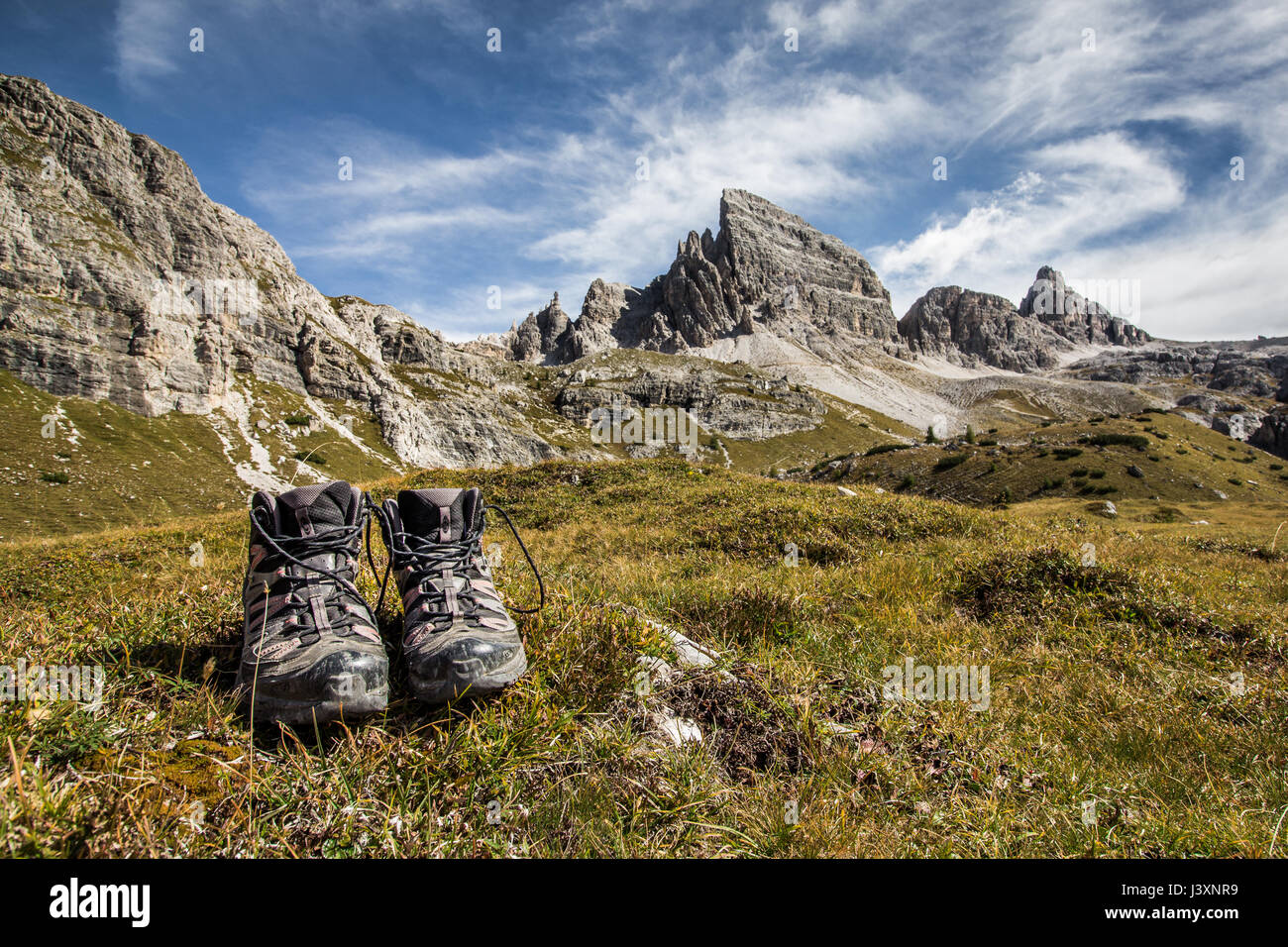 Trekking shoes (boots) on grass in front of stunning mountain scenery and  blue skies clear weather. The mountain in the background is Monte Paterno,  P Stock Photo - Alamy