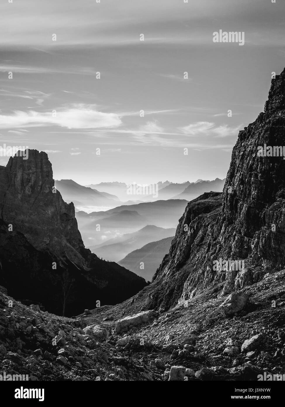 Black and white landscape view of hazy rolling mountains and hills in the Italian Dolomites at sunrise. Portrait orientation. Stock Photo