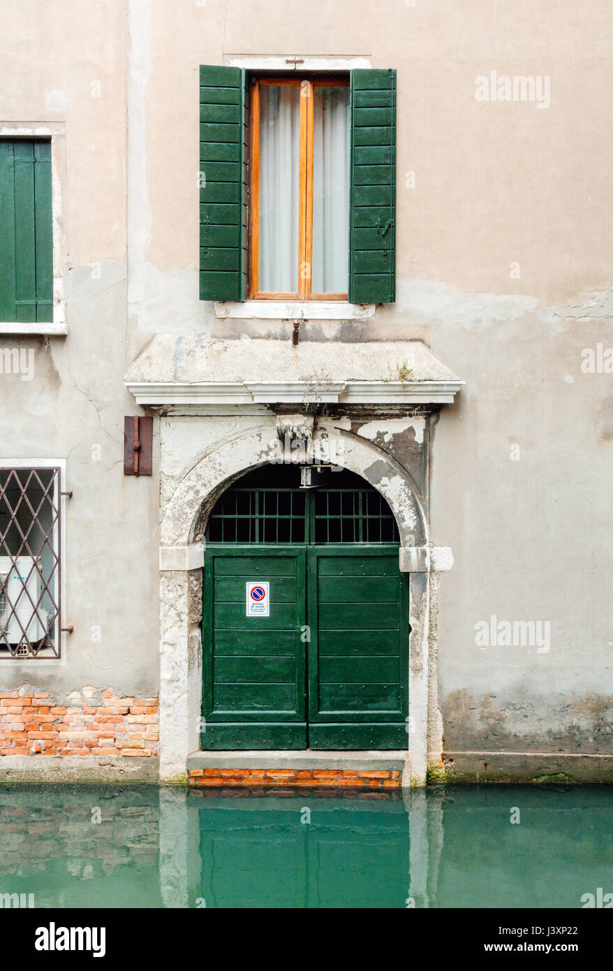 Residential garage door and window in Venice, italy leading onto one of the many canals used as streets for travelling around the city. Stock Photo
