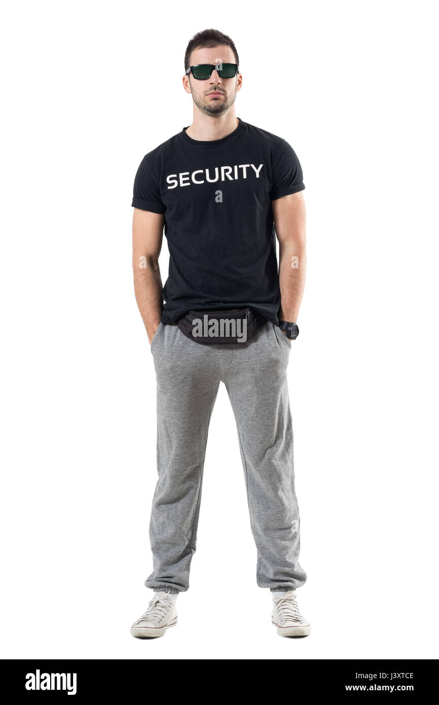 Tough confident macho young undercover cop with hands in pockets looking at camera. Full body length portrait isolated on white studio background. Stock Photo