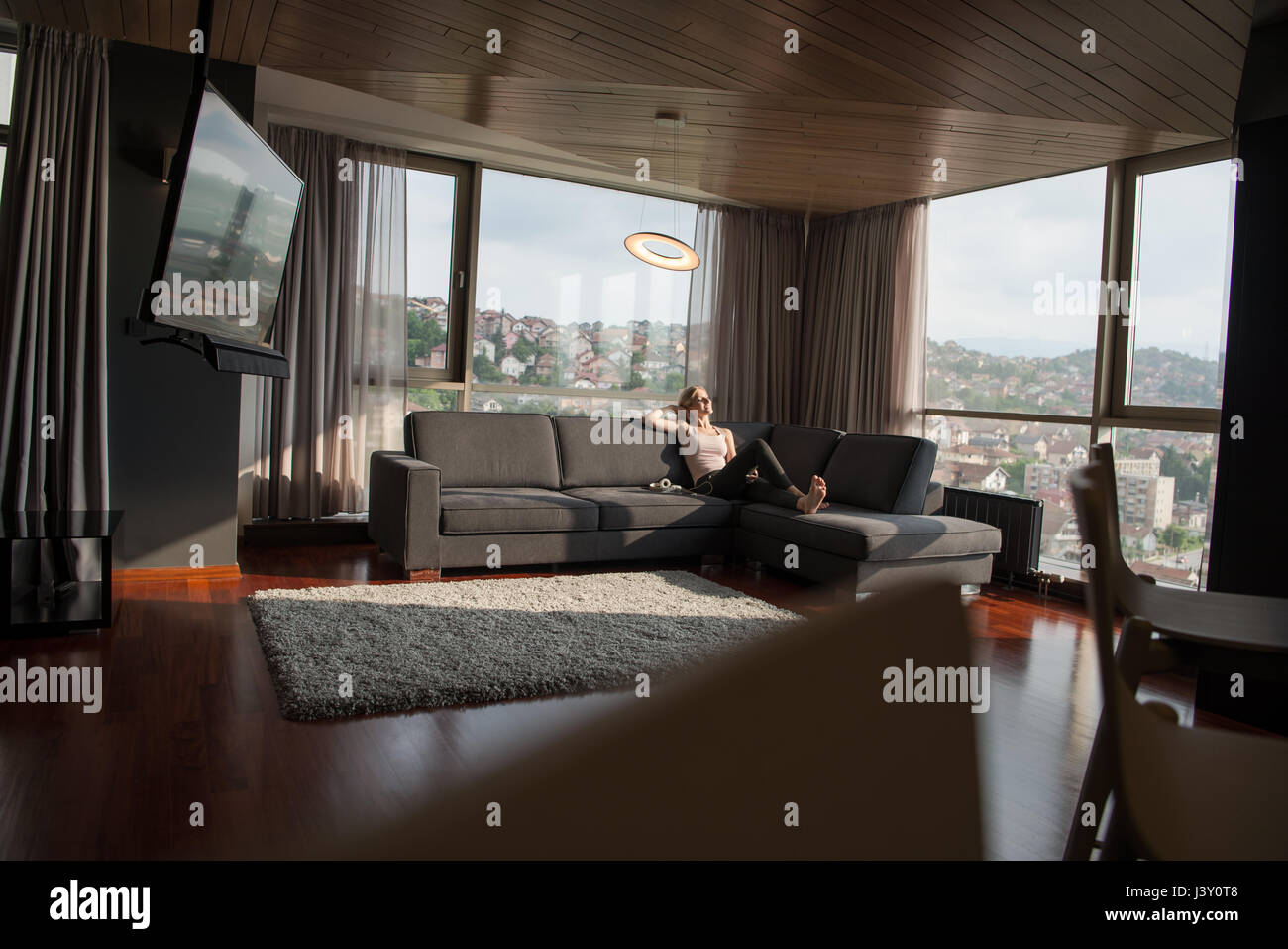 Blonde Woman Sitting On A Sofa Using Her Tablet Stock Photo - Alamy