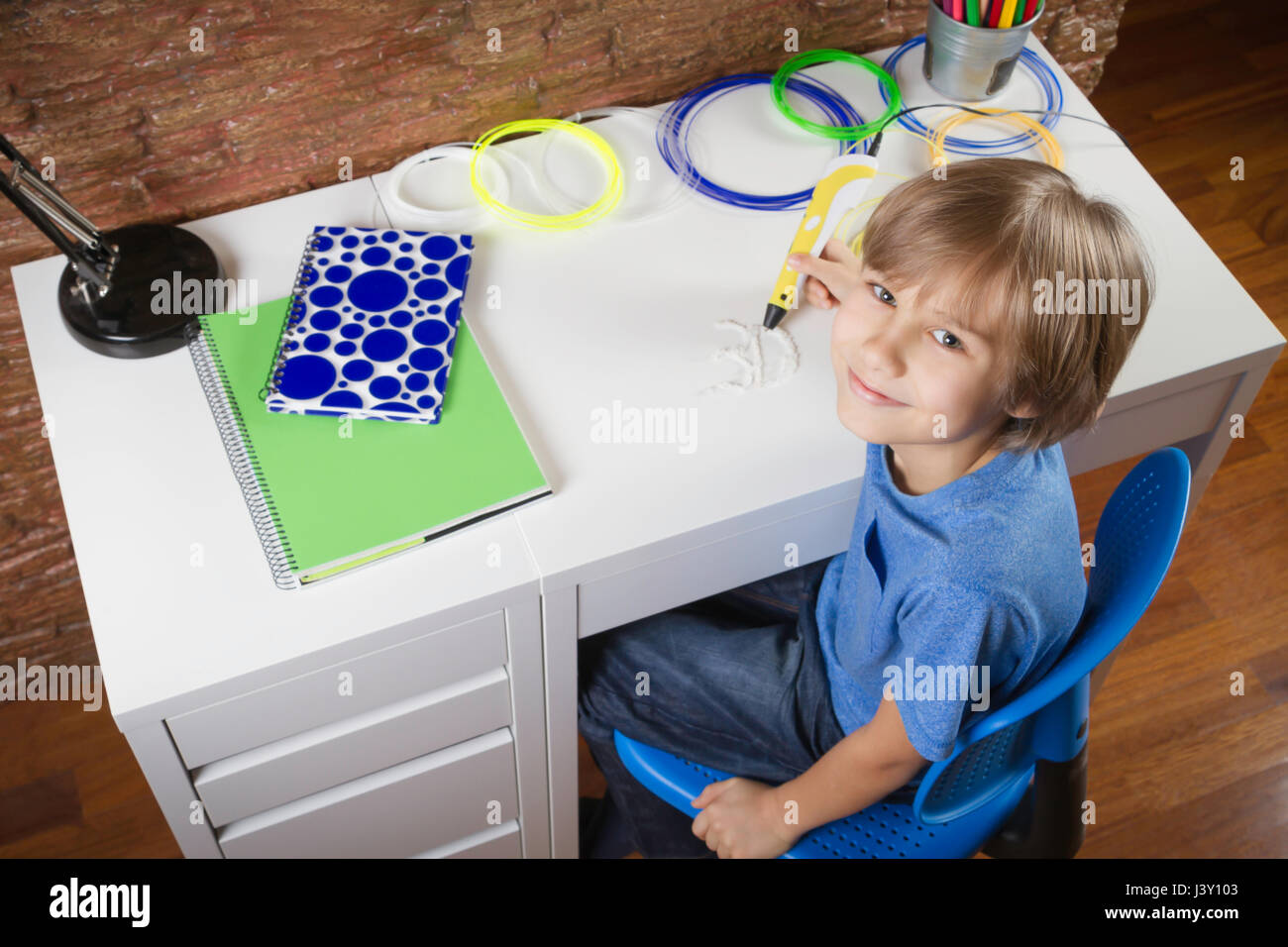 Happy child creating with 3D printing pen. Boy making new item ...