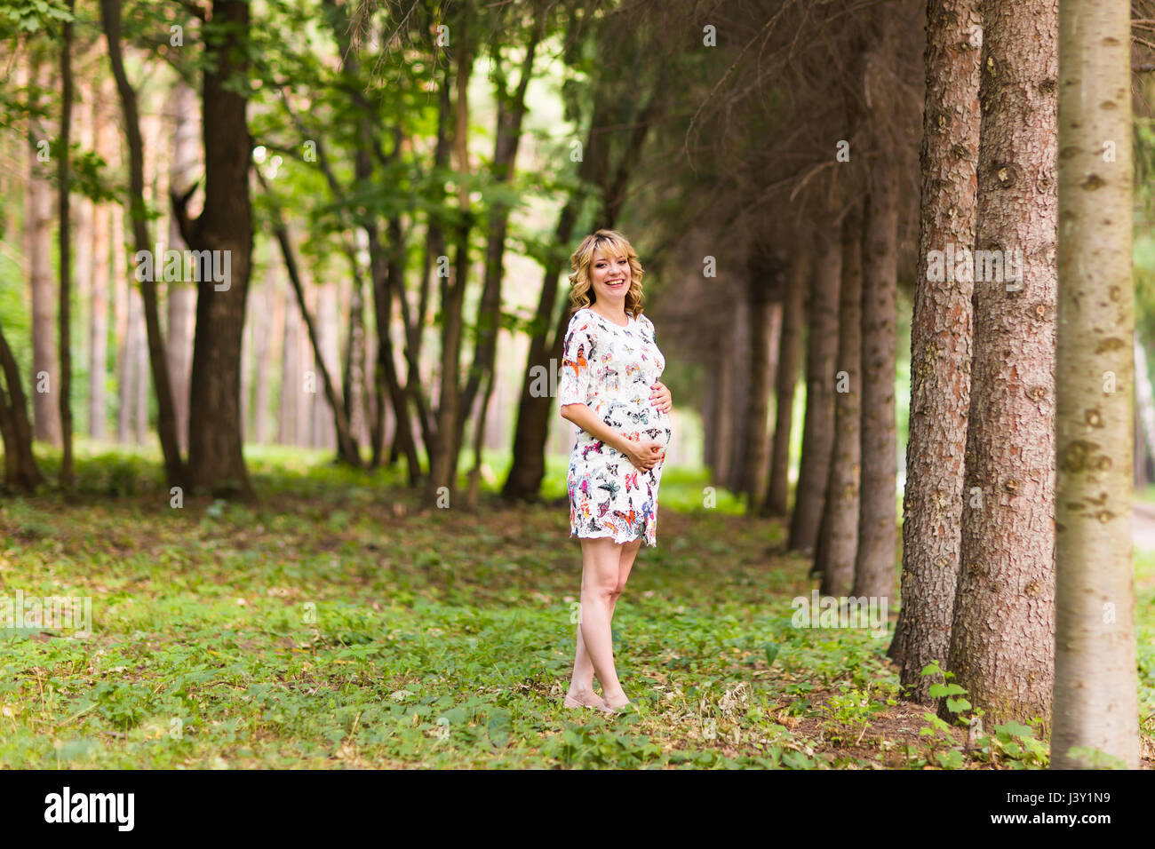 Beautiful pregnant woman touches her belly in the park Stock Photo - Alamy