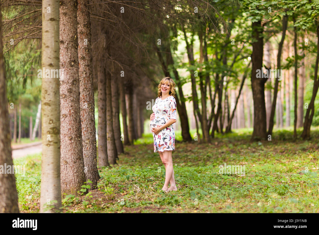 Beautiful pregnant woman touches her belly in the park Stock Photo - Alamy