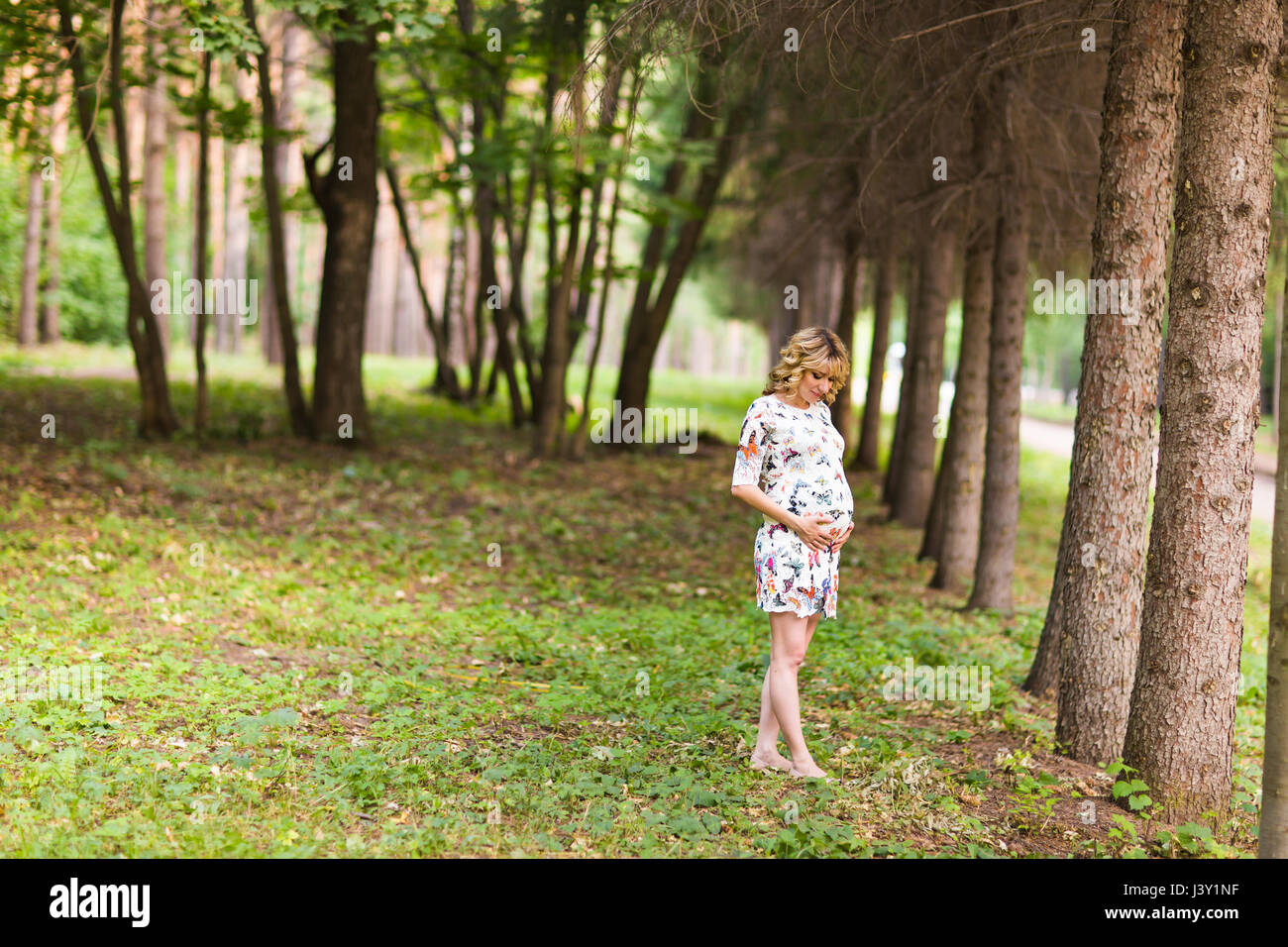 Beautiful pregnant woman touches her belly in the park Stock Photo - Alamy