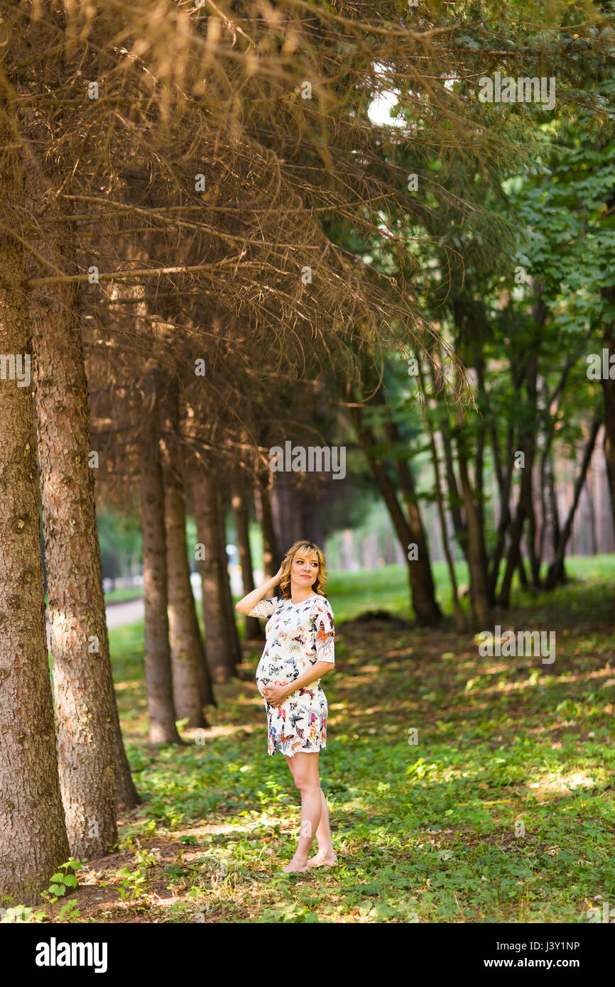 Beautiful pregnant woman touches her belly in the park Stock Photo - Alamy