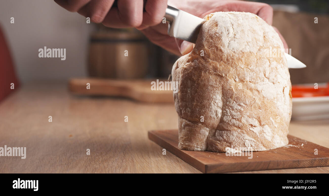 young man hands cutting ciabatta bread for making sandwich Stock Photo
