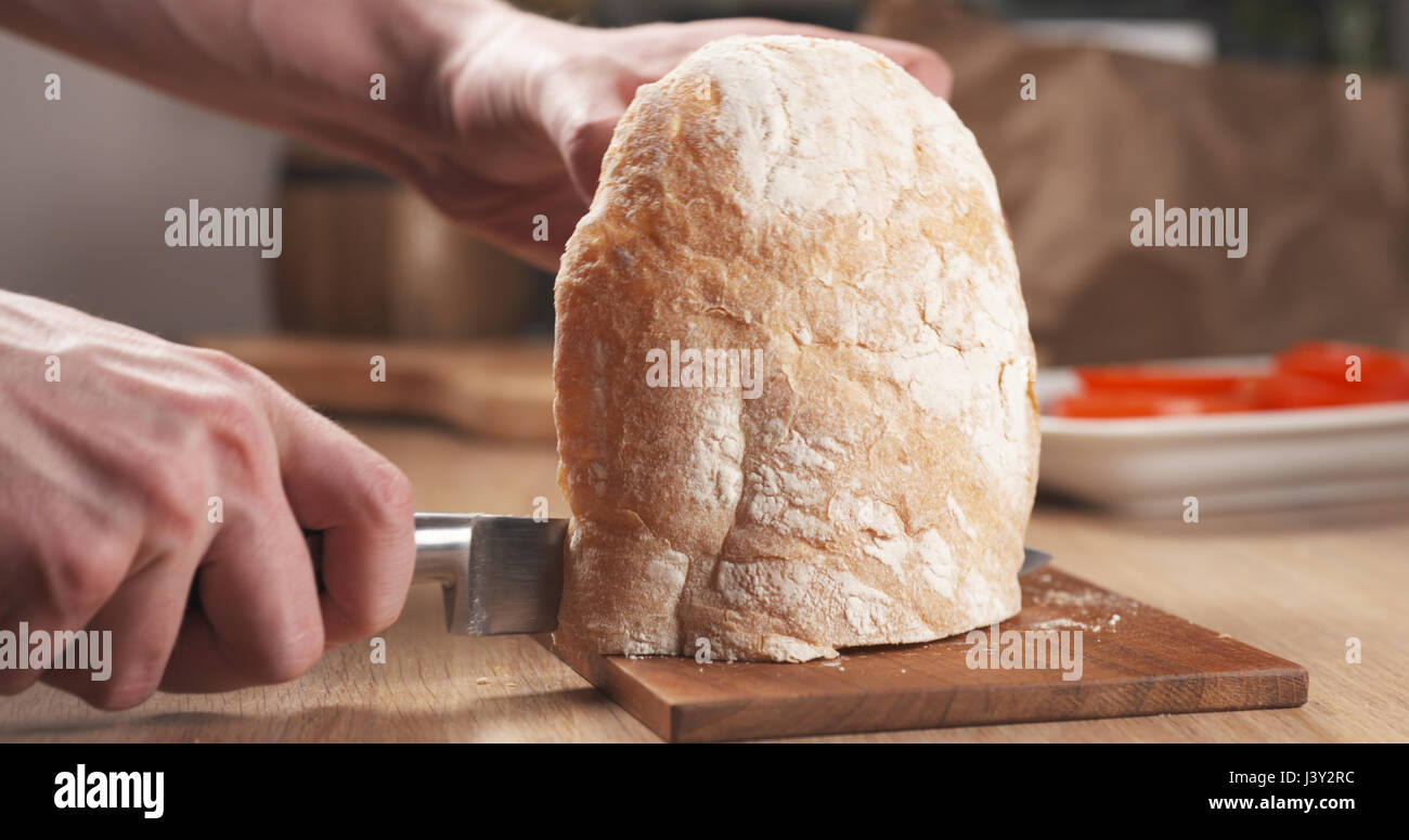 young man hands cutting ciabatta bread for making sandwich Stock Photo