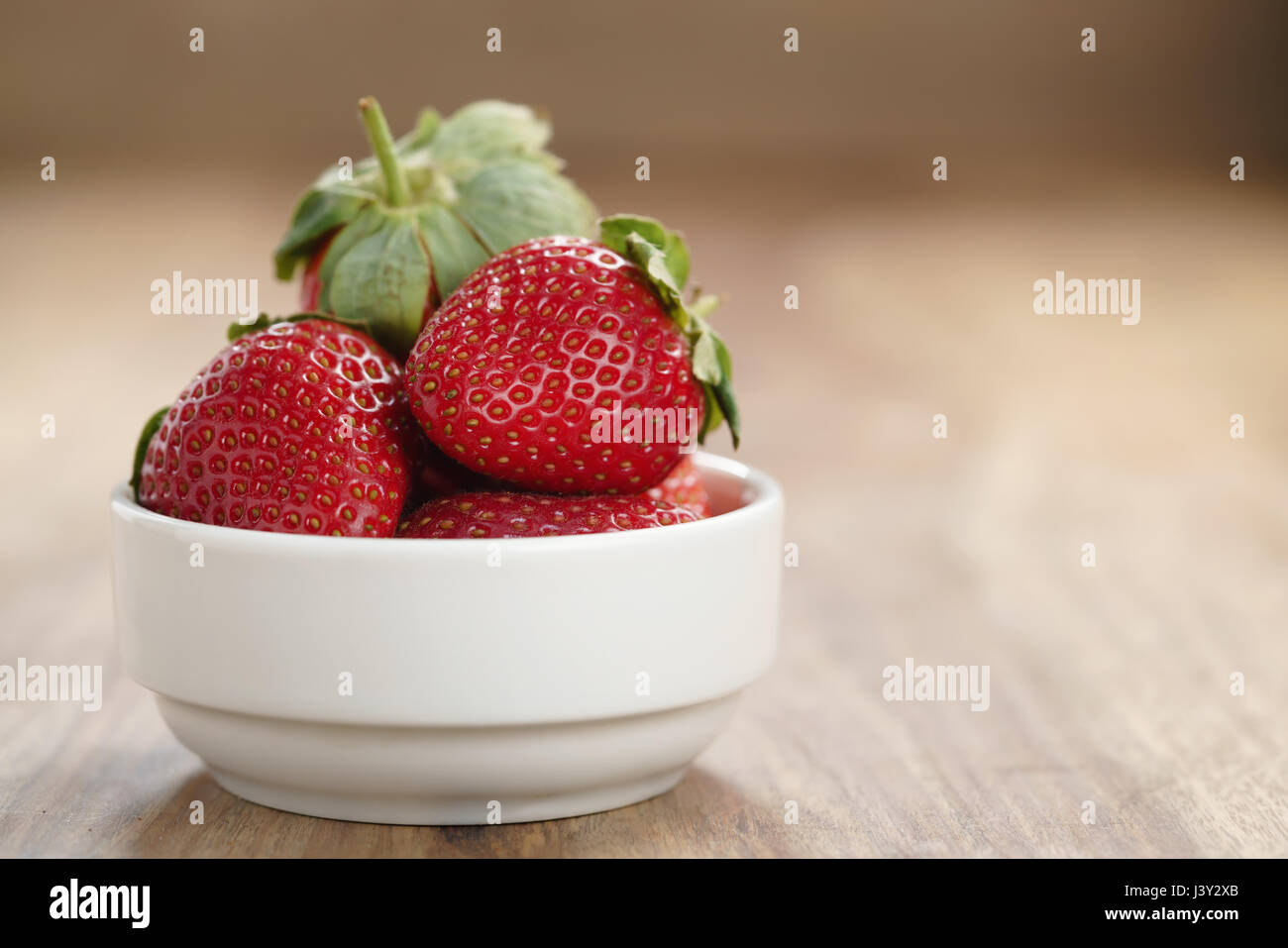 ripe organic strawberries in white bowl on wood table Stock Photo - Alamy