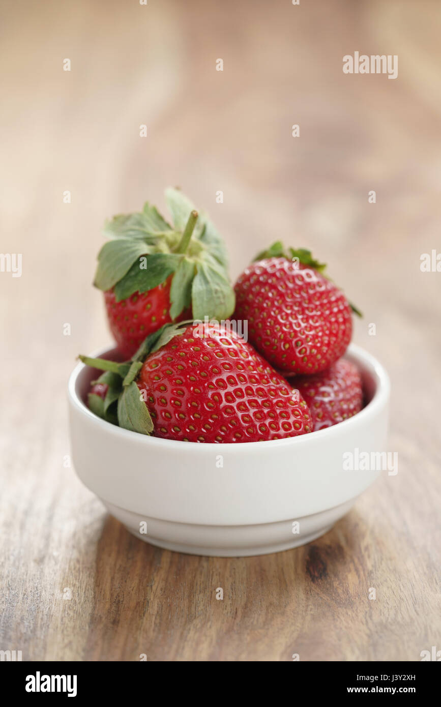ripe organic strawberries in white bowl on wood table Stock Photo - Alamy