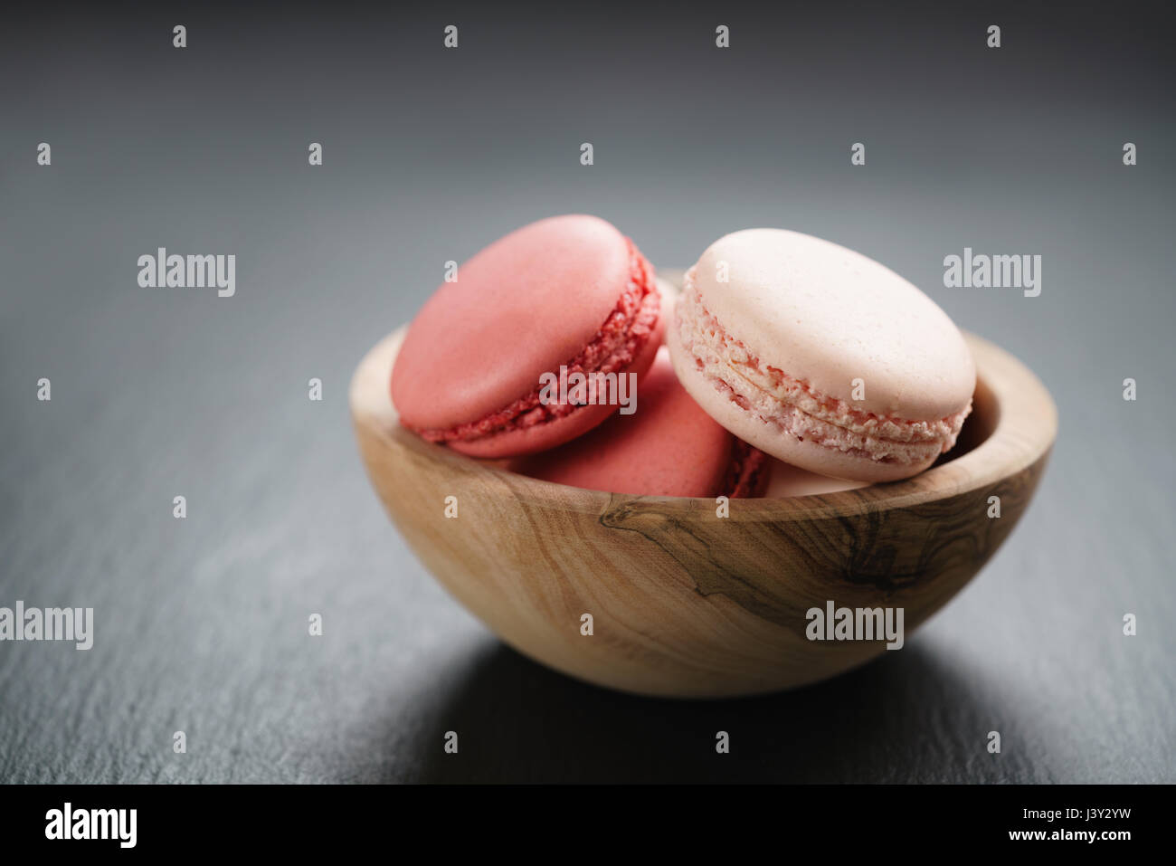 pink macarons in bowl on slate background with copy space Stock Photo