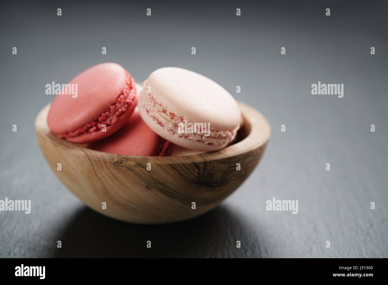 pink macarons in bowl on slate background with copy space Stock Photo
