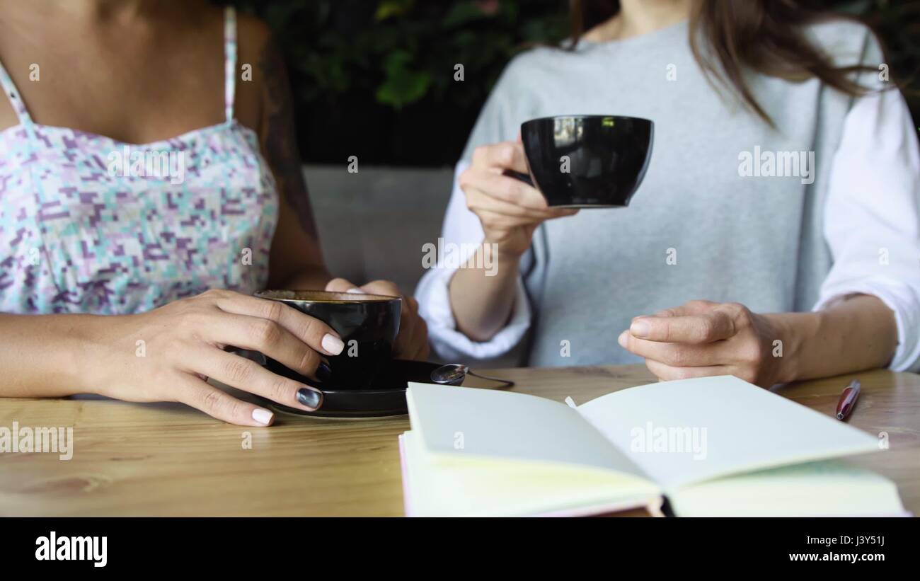 Two women friends drink cacao in cafe. Females talking and drinking