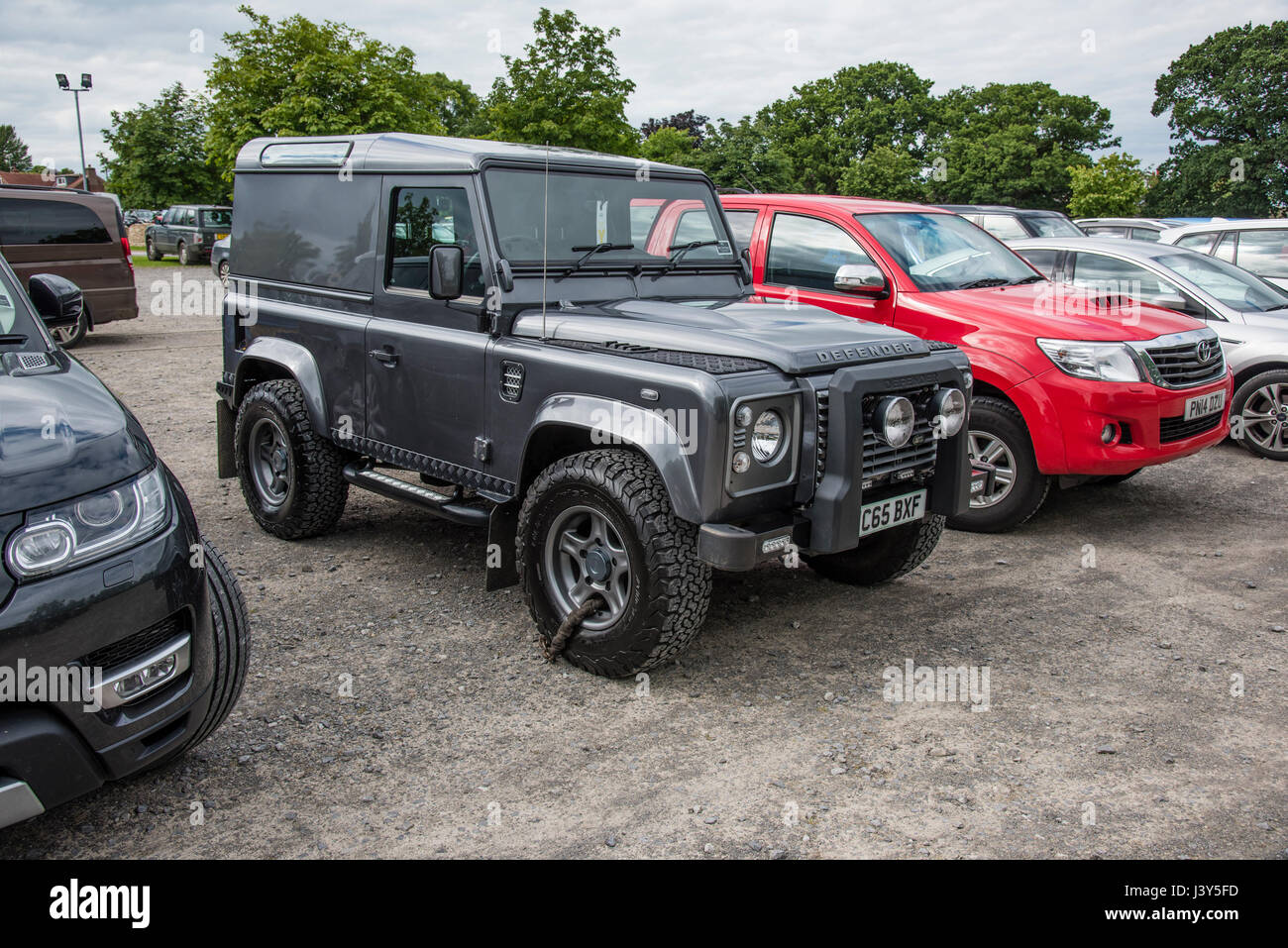 A new Landrover Defender with chain round the front wheel as theft protection in a car park, Harrogate, North Yorkshire. Stock Photo