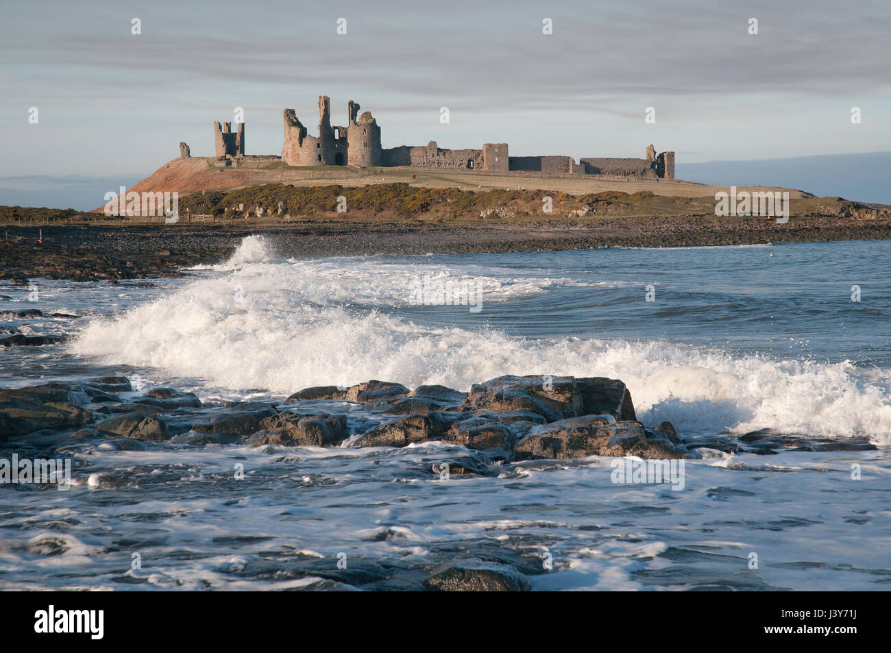 Dunstanburgh Castle on its Whin Sill outcrop, seen from the south. The castle, built in the 14th century, fell into disrepair by the 16th century. Stock Photo
