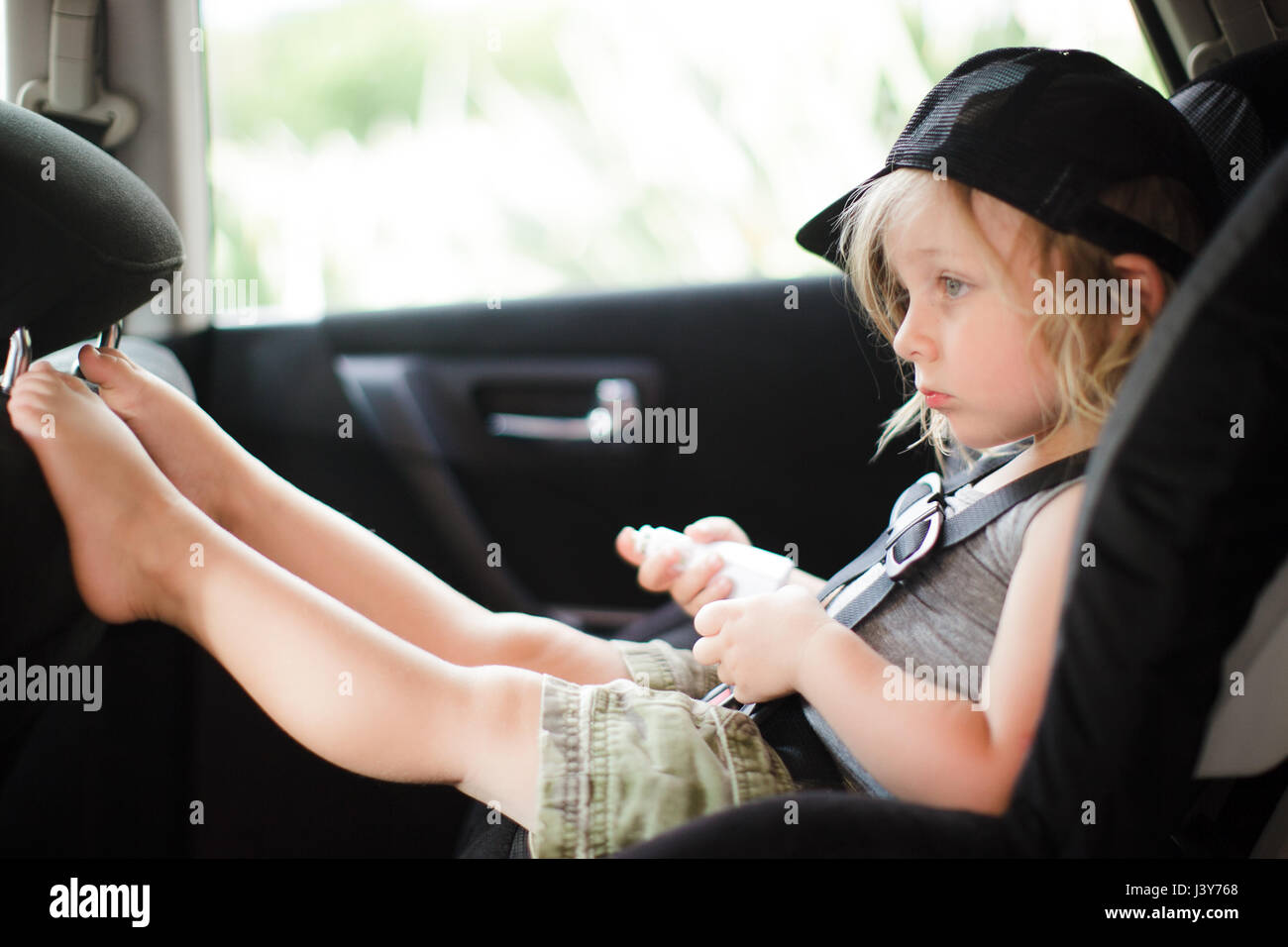 Male toddler with feet up staring in back seat of car Stock Photo - Alamy