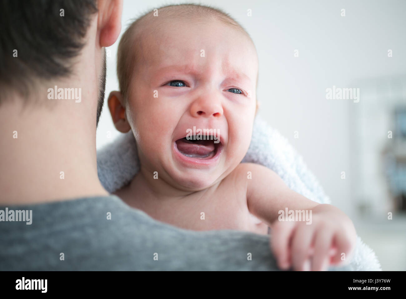 Over shoulder view of man carrying crying baby son Stock Photo Alamy