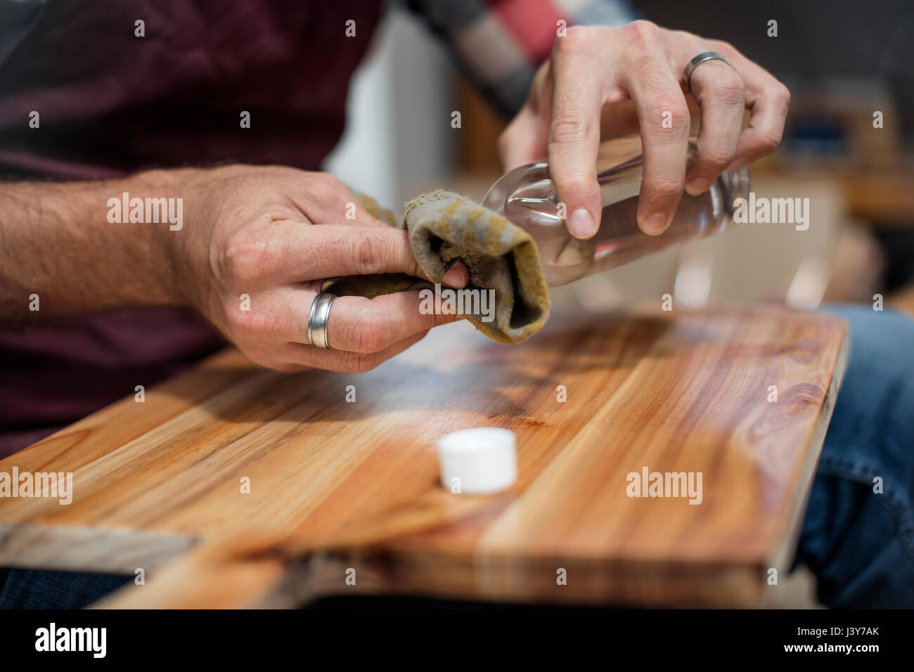 Close up of male hands applying wood stain to chopping board in factory Stock Photo