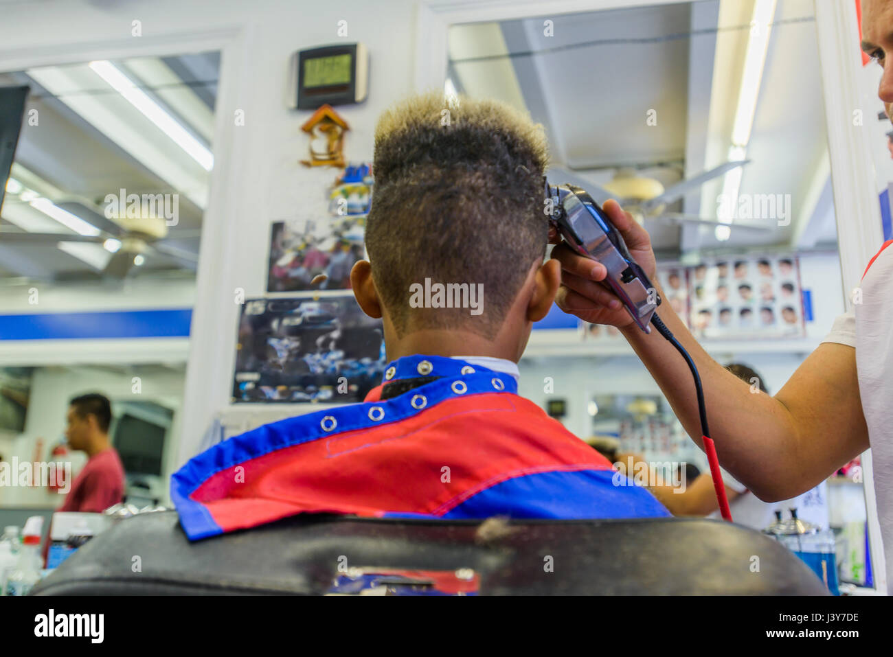 Hairdresser cutting teenage boy's hair in barbershop Stock Photo