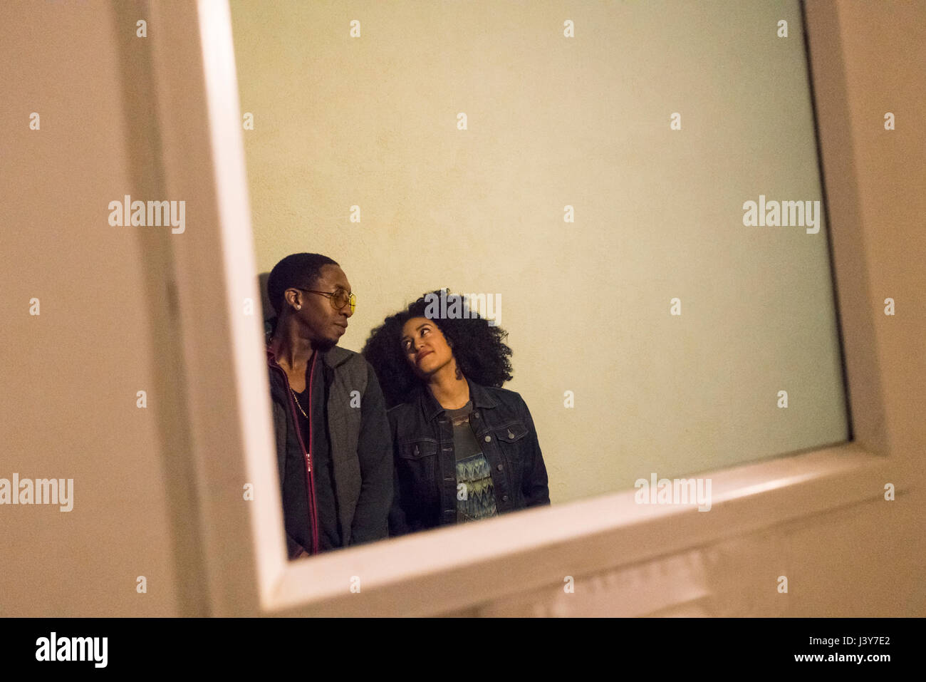 View through glass pane in door of couple Stock Photo