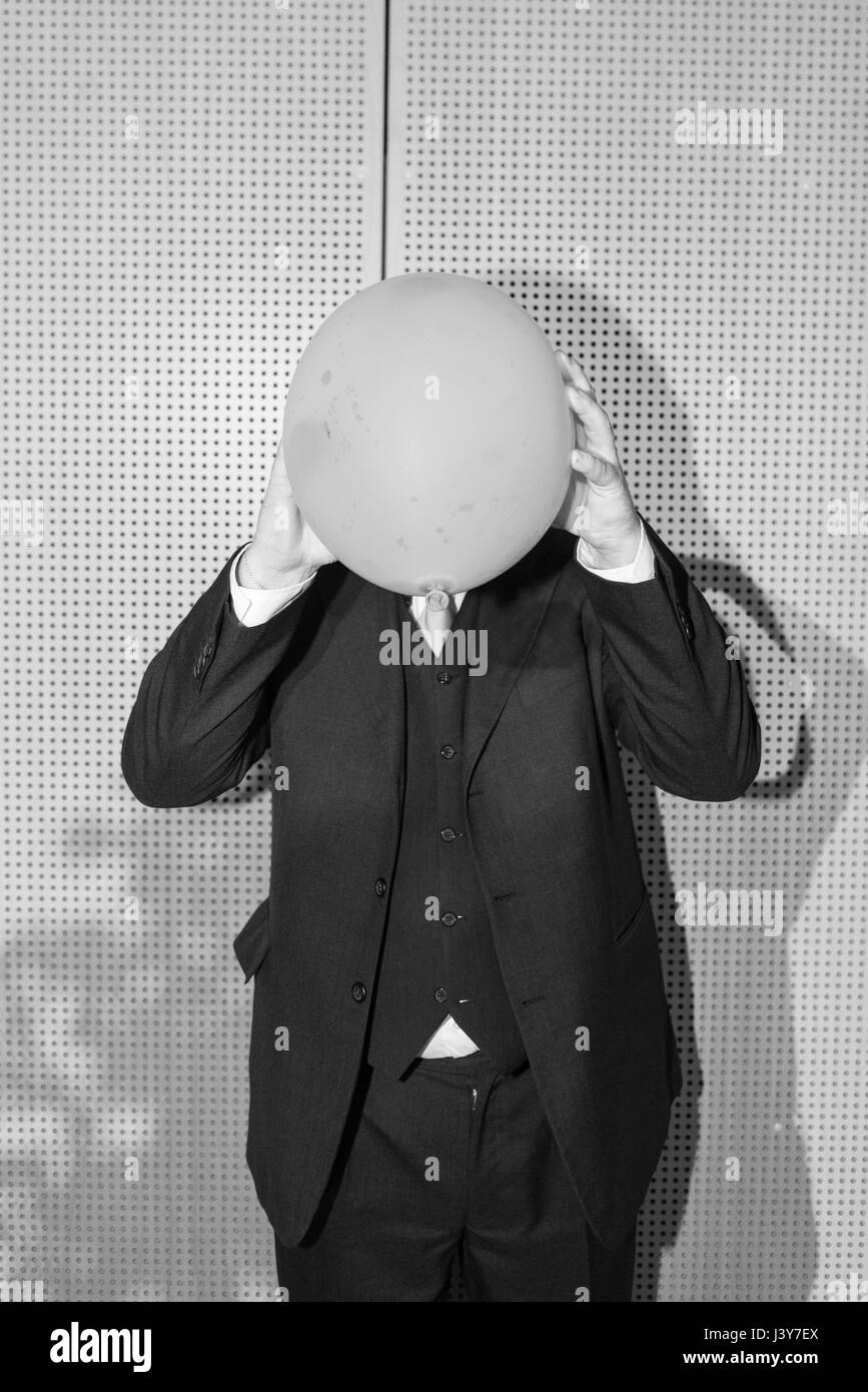 Man wearing suit, face obscured by balloon Stock Photo