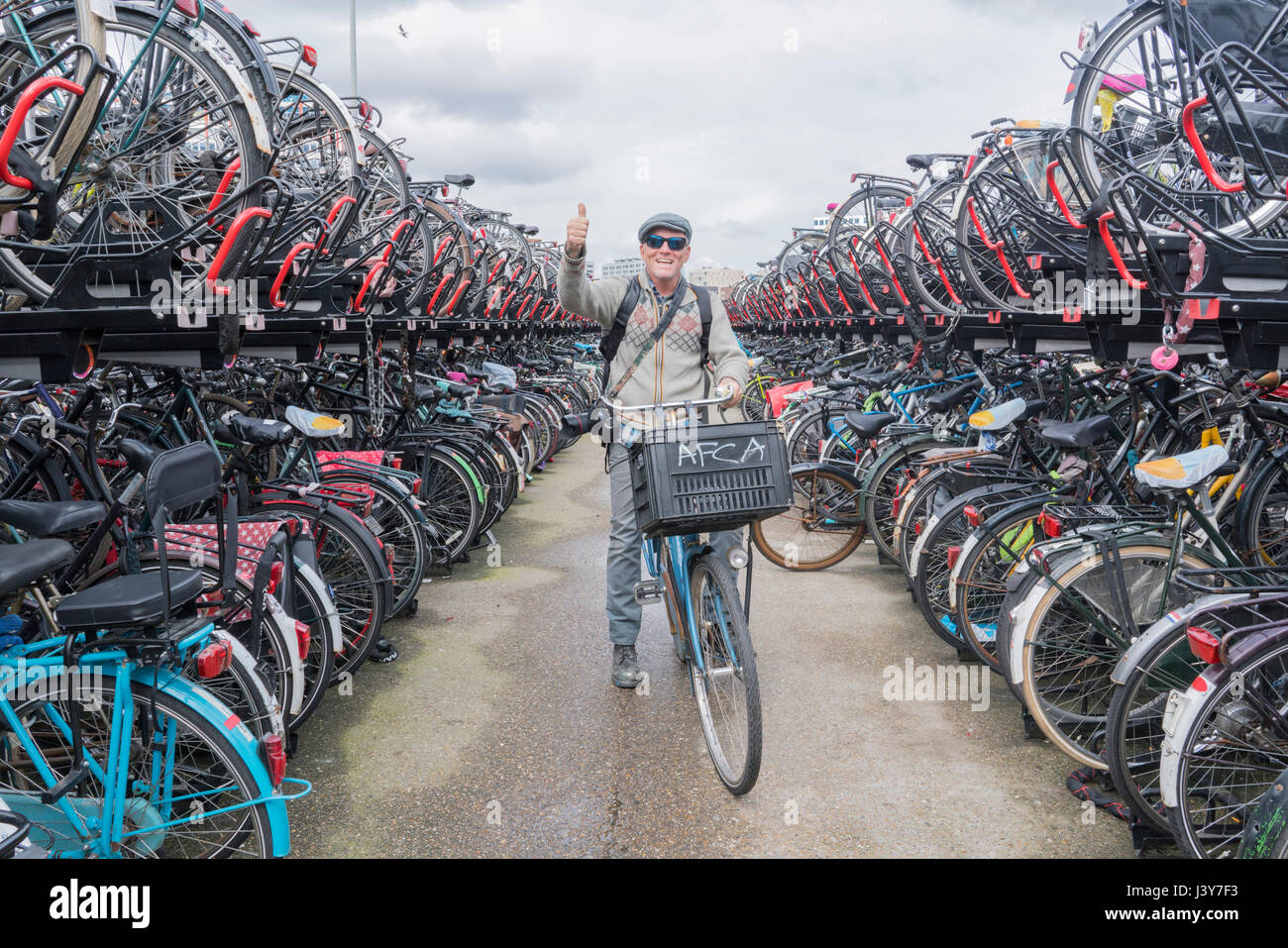 Cyclist on bicycle looking at camera giving thumbs up, Amsterdam, Netherlands Stock Photo