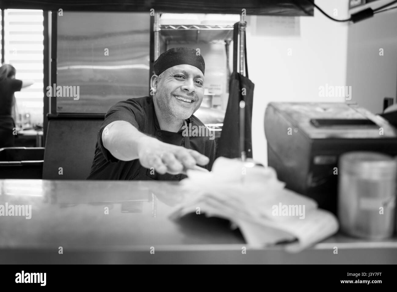 Chef in commercial kitchen smiling at camera Stock Photo