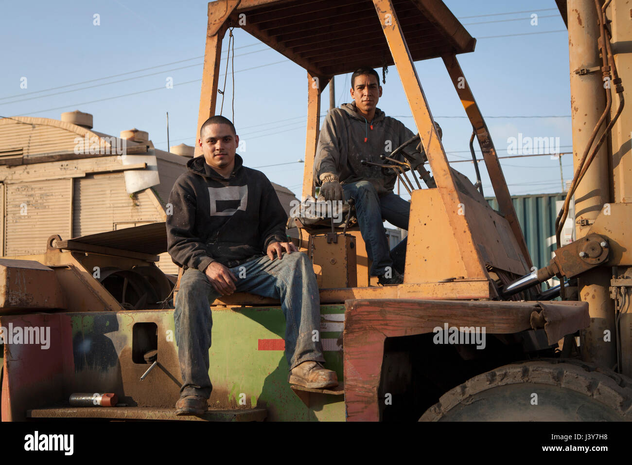 Colleagues on construction site sitting on heavy machinery Stock Photo