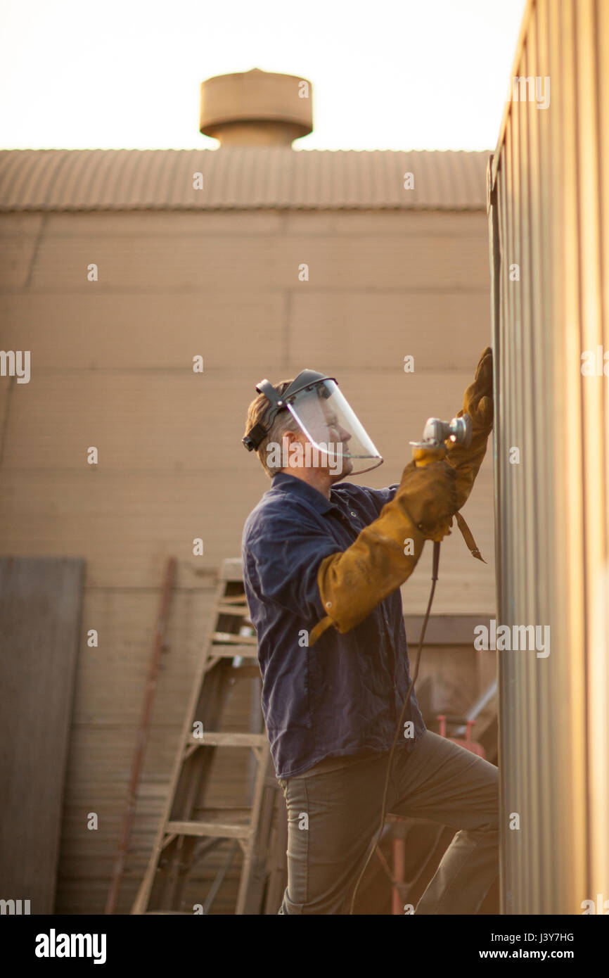 Welder using power tool on shipping container Stock Photo Alamy