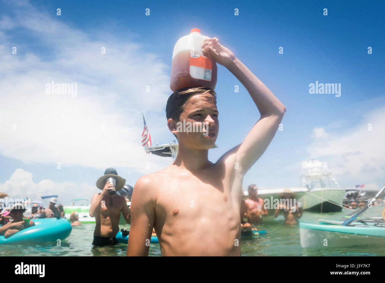 Teenage boy in water holding juice carton on head, Crab Island, Emerald Coast, Gulf of Mexico, USA Stock Photo
