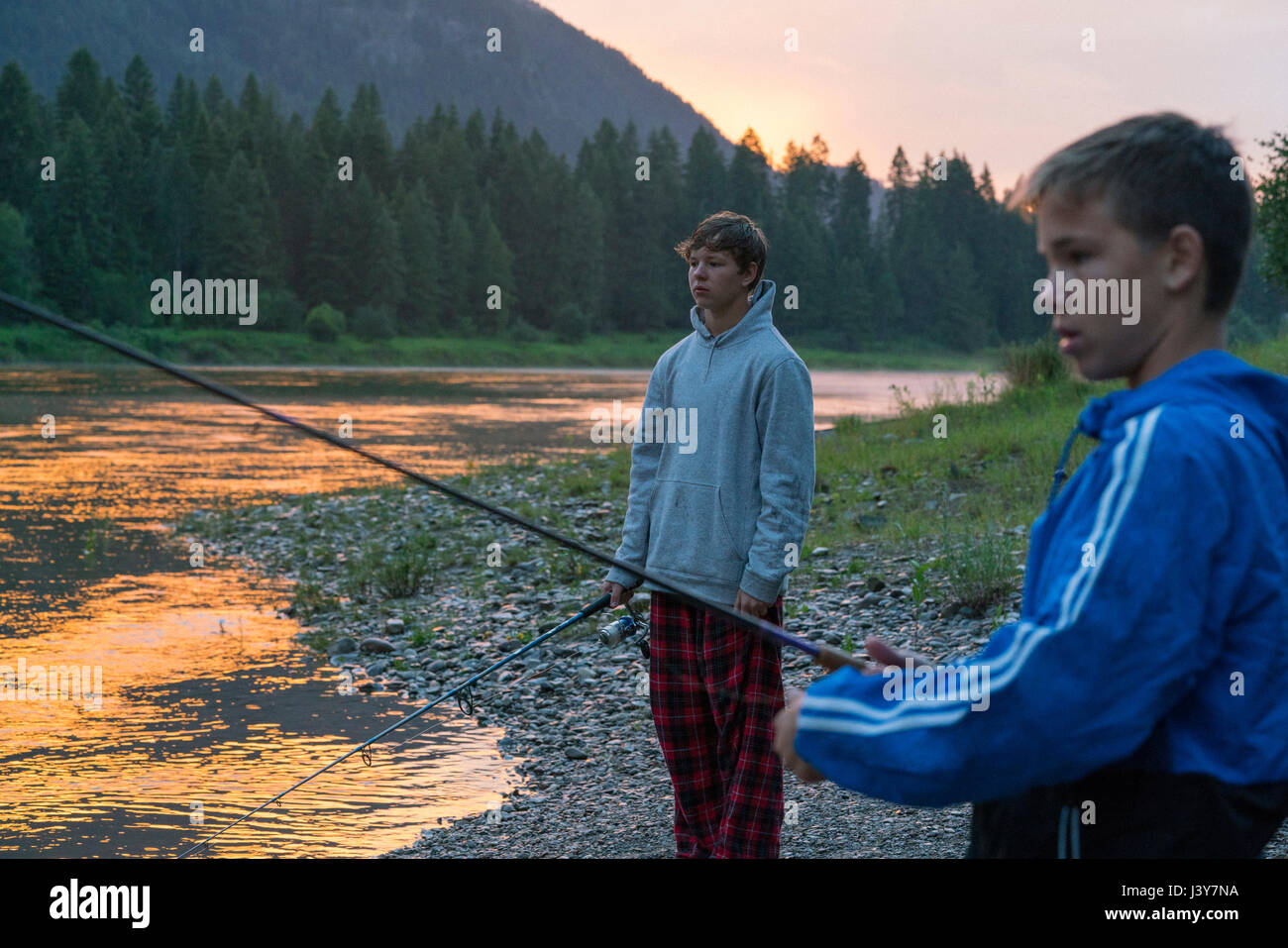Teenage boys fishing in river at sunset, Washington, USA Stock Photo