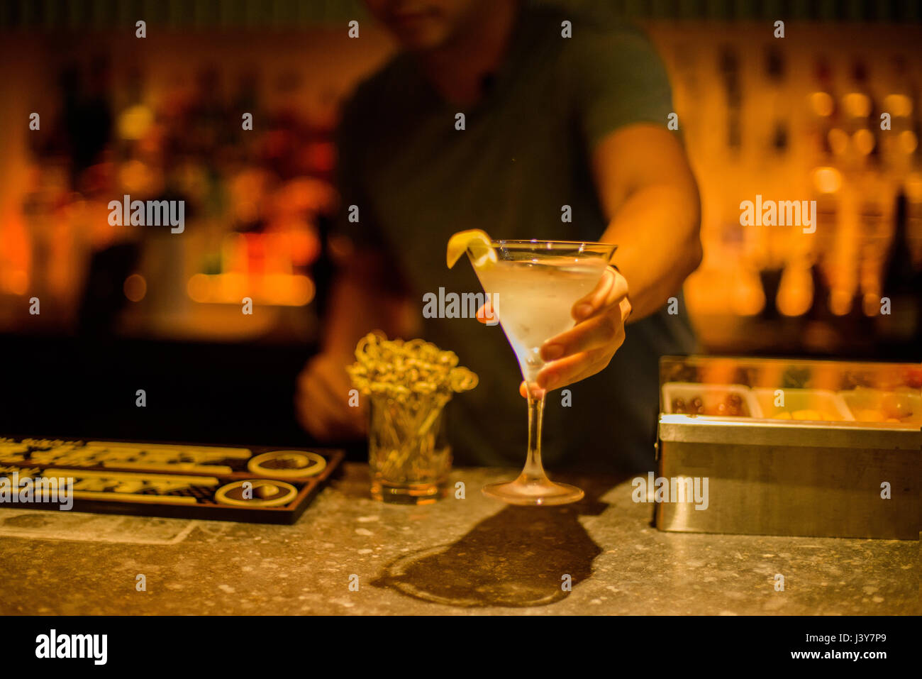Bar tender serving cocktail drink over bar Stock Photo