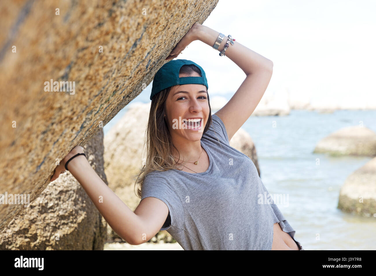 Girl Looking Over Rocks Portrait of teenage girl on rocks by sea looking at camera smiling ...