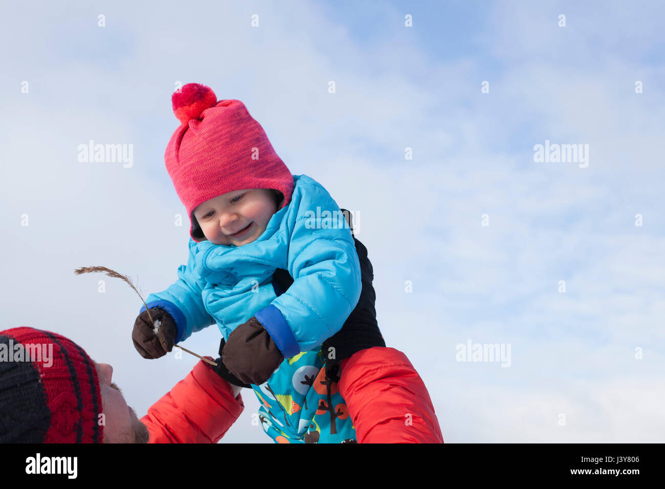 Father lifting young son in air, in snow covered landscape Stock Photo