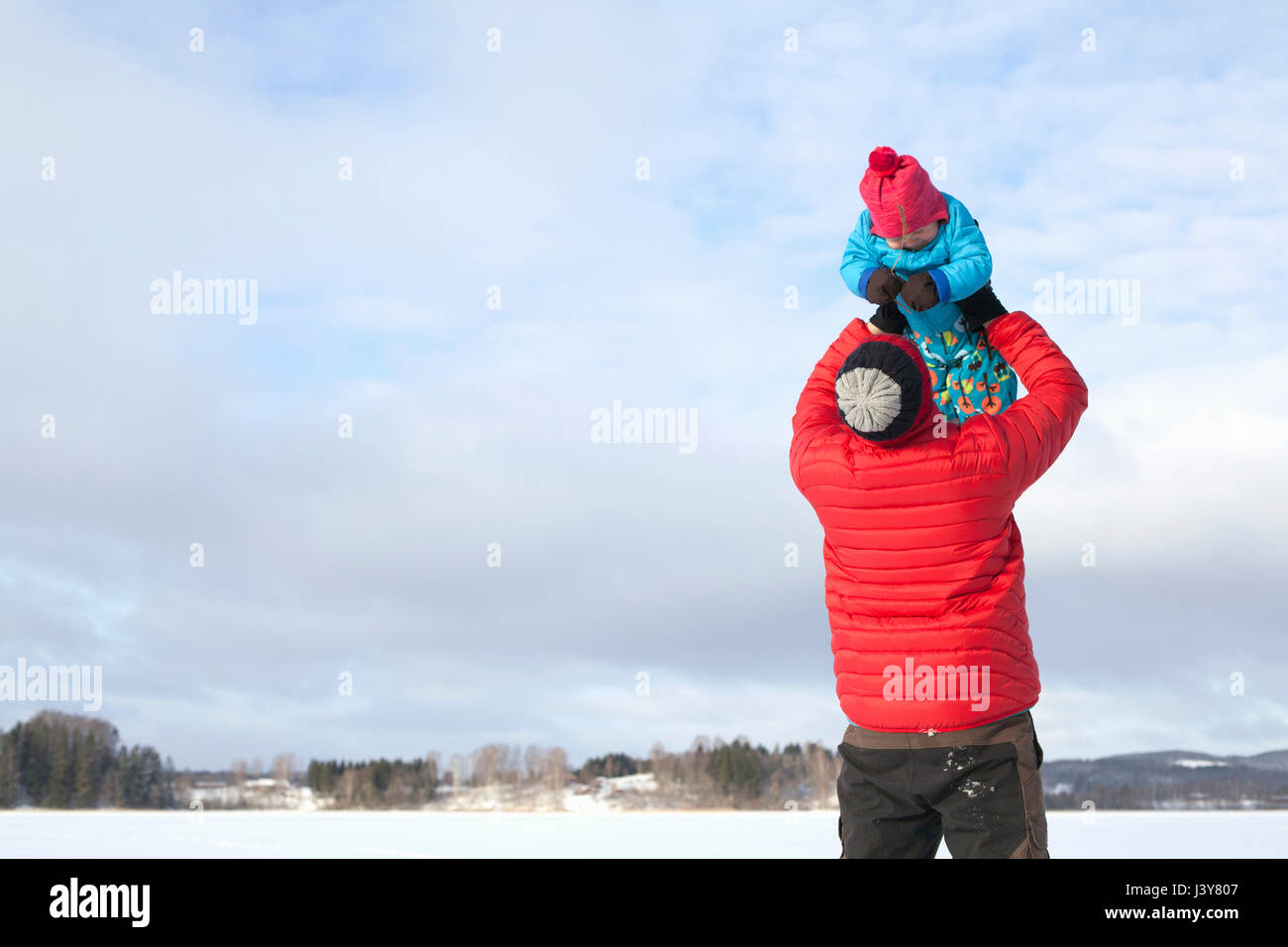 Father lifting young son in air, in snow covered landscape Stock Photo