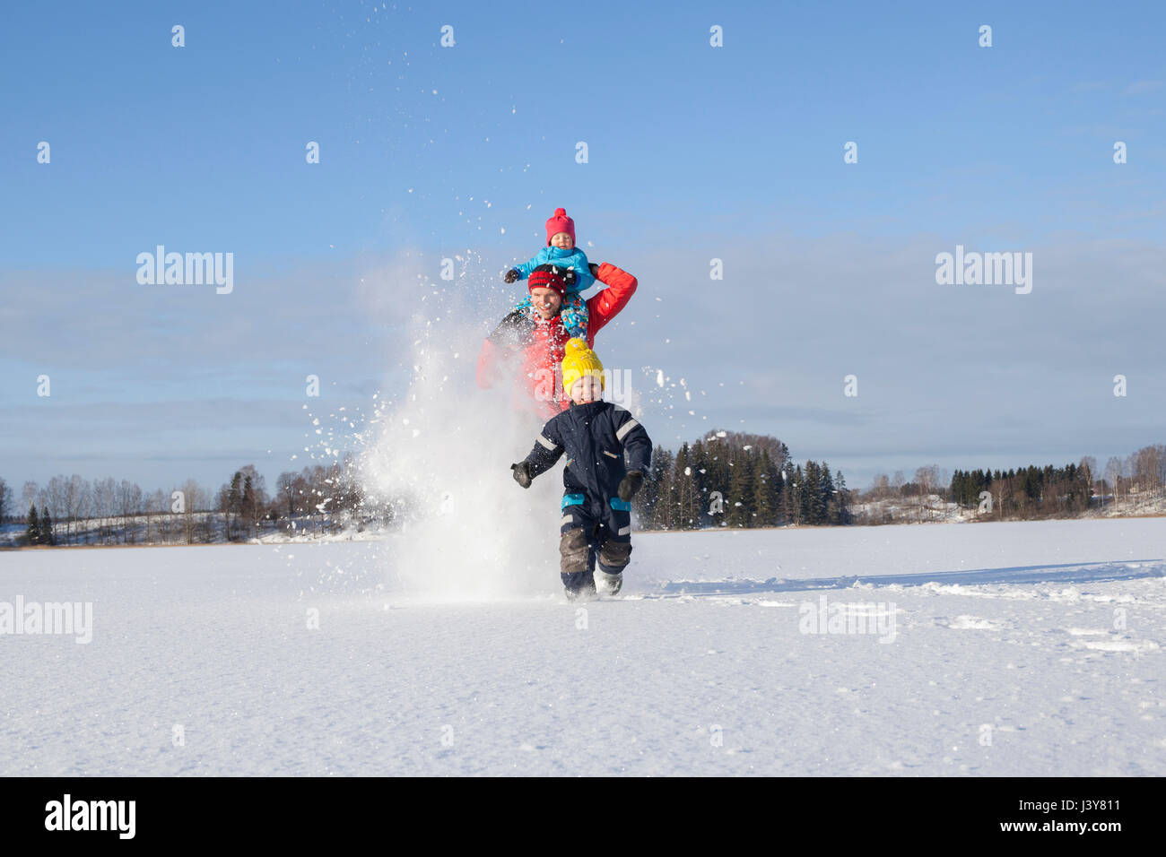 Father and two sons fooling around, running through snow covered