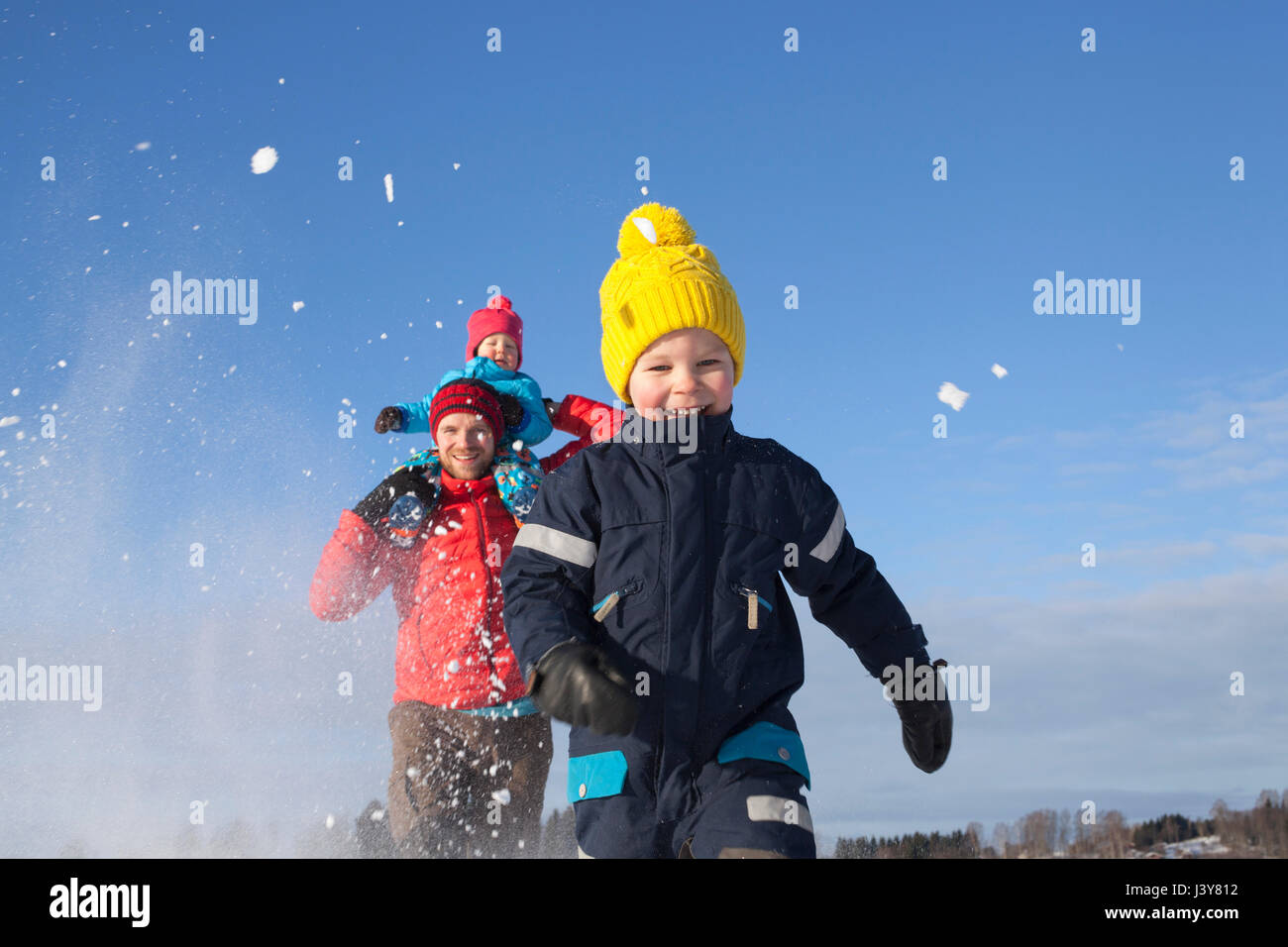Father and two sons fooling around, running through snow covered