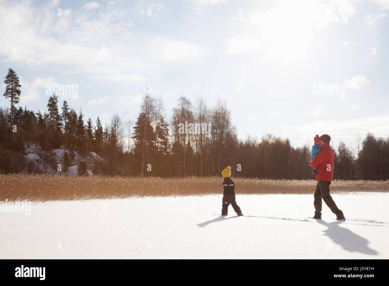 Father and two sons, walking through snow covered landscape Stock Photo