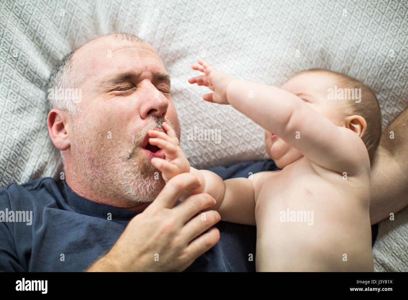 Mature man and baby daughter lying on bed, head and shoulders Stock Photo