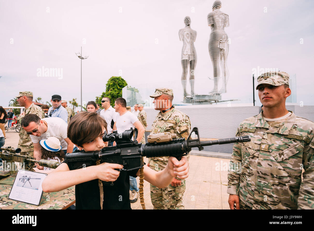 Batumi, Adjara, Georgia - May 26, 2016: Boy holding M4 assault rifle at an exhibition of weapons during celebration of the national holiday - the Inde Stock Photo