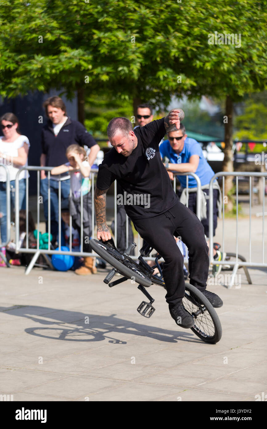 A stunt cyclist riding a bike / cycle during an exhibition performing stunts / wheelies and other trick / tricks. UK. (87) Stock Photo