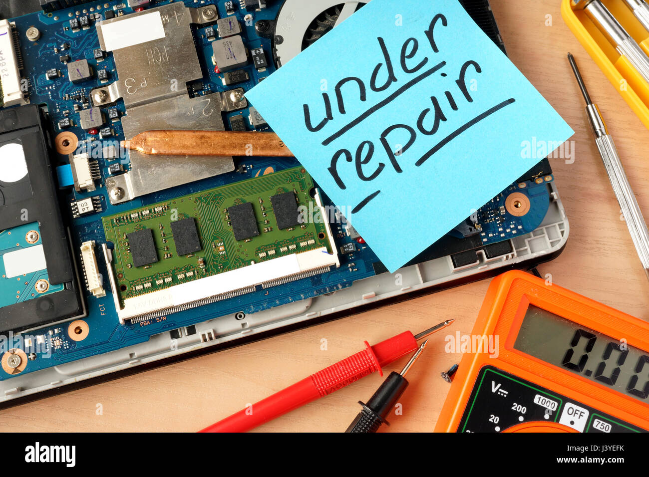 Broken laptop and stick with words under repair. Stock Photo