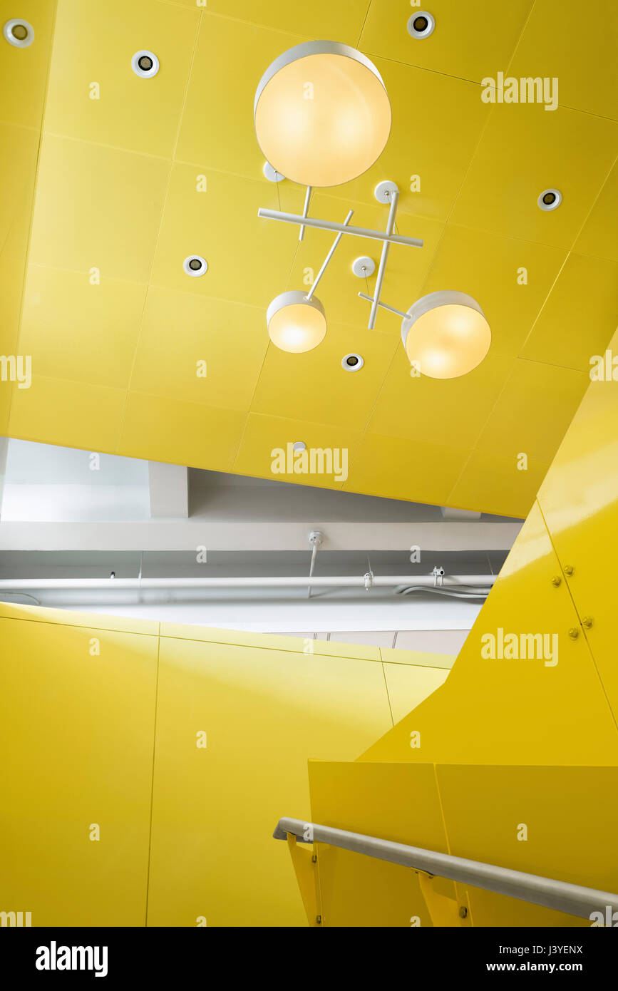 Interior detail of light fixture above yellow painted steel staircase. 2 Lafayette Street  NYC Department of Youth, New York, United States. Architect Stock Photo