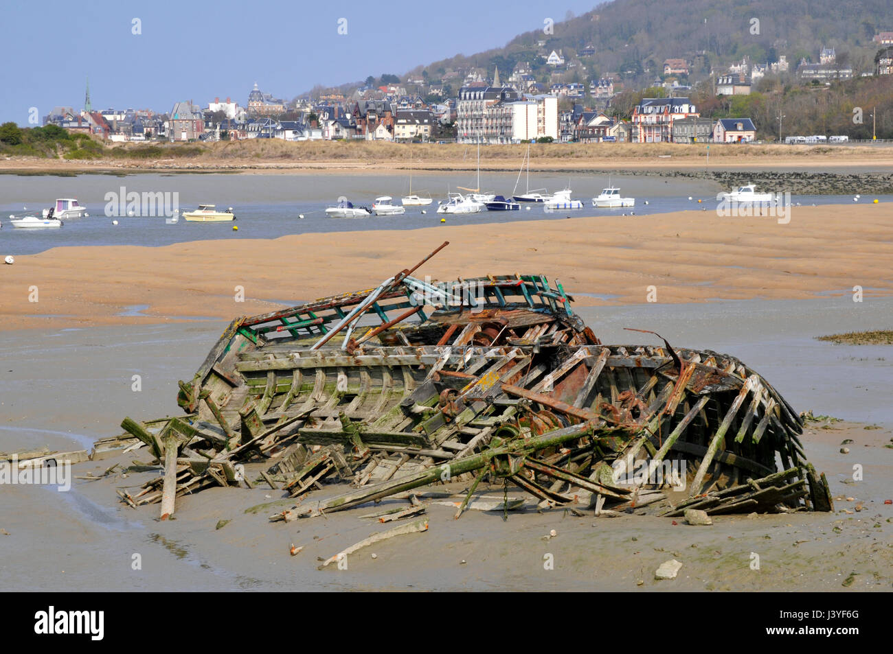 Shipwreck boat on the beach of Dives sur Mer in France with the commune of Hougalte in the background, in the Calvados department in France Stock Photo