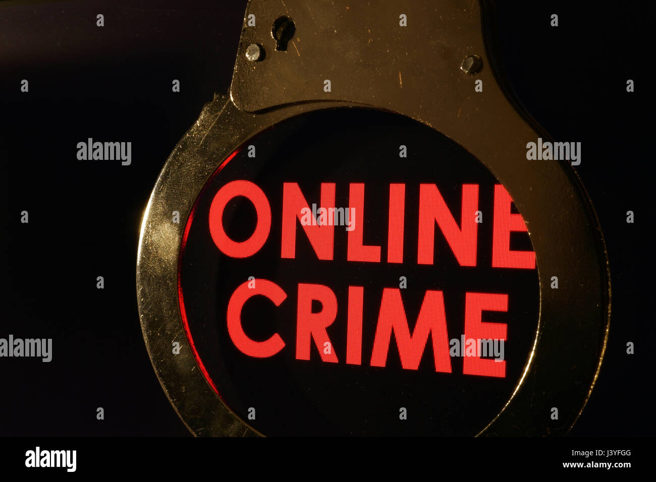 Words Online crime on a monitor and handcuffs. Stock Photo