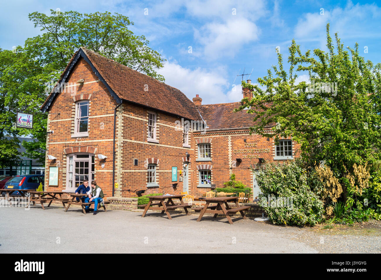 Two men drinking at a table outside the Cricketers' Arms pub, Rickling Green, Hertfordshire, England in summer Stock Photo