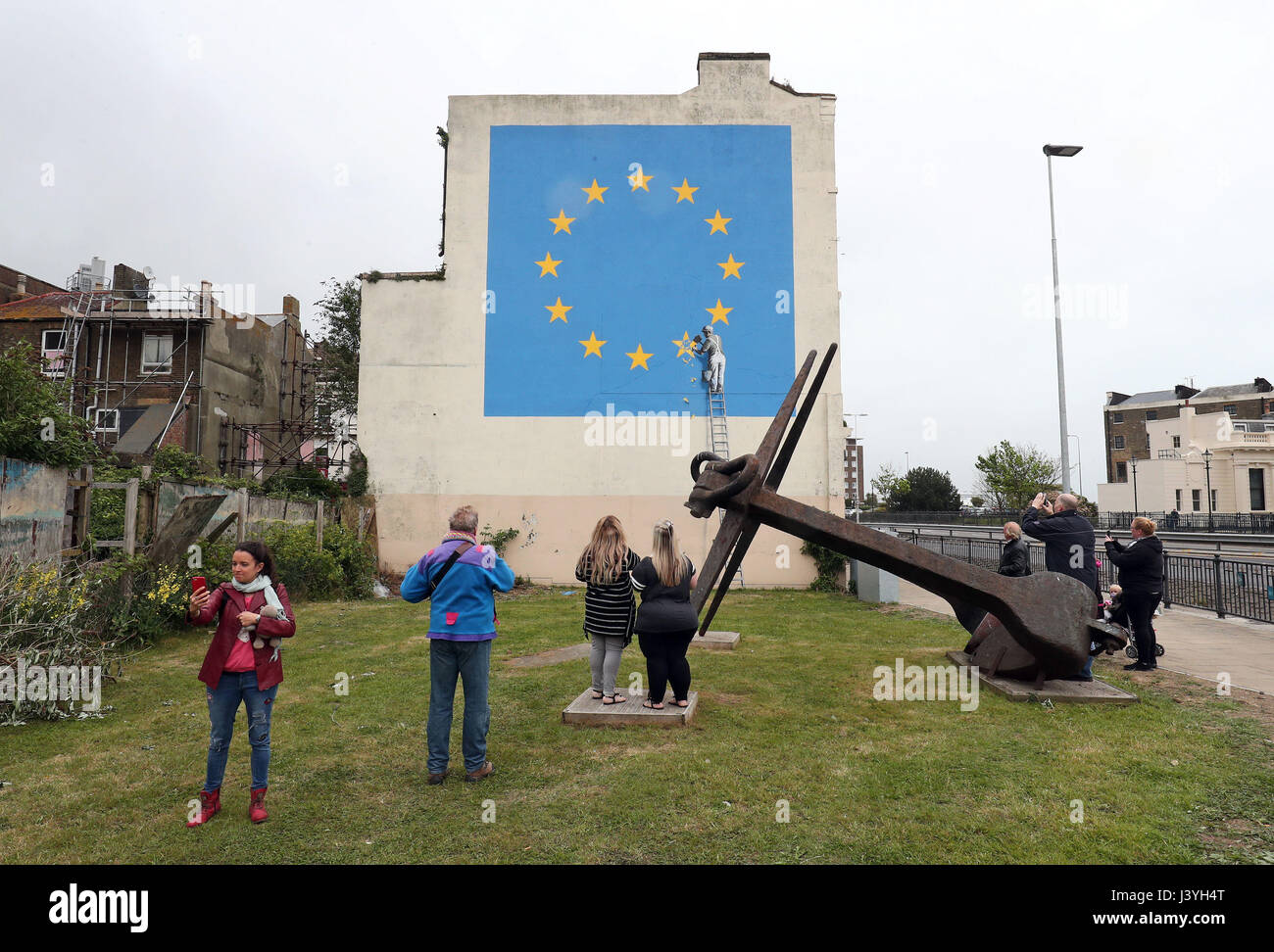 People stop to view a mural by artist Banksy of a workman removing a star from the EU flag which appeared yesterday near the ferry terminal in Dover, Kent. Stock Photo