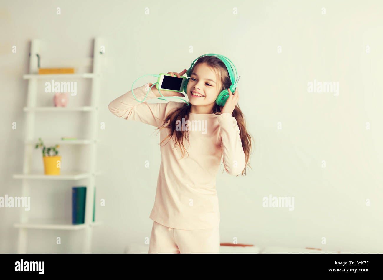 girl jumping on bed with smartphone and headphones Stock Photo Alamy