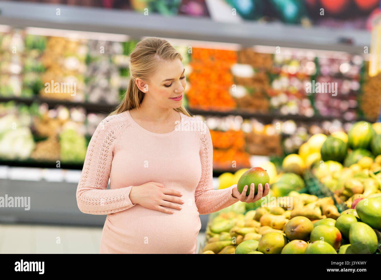 happy pregnant woman with mango at grocery store Stock Photo Alamy
