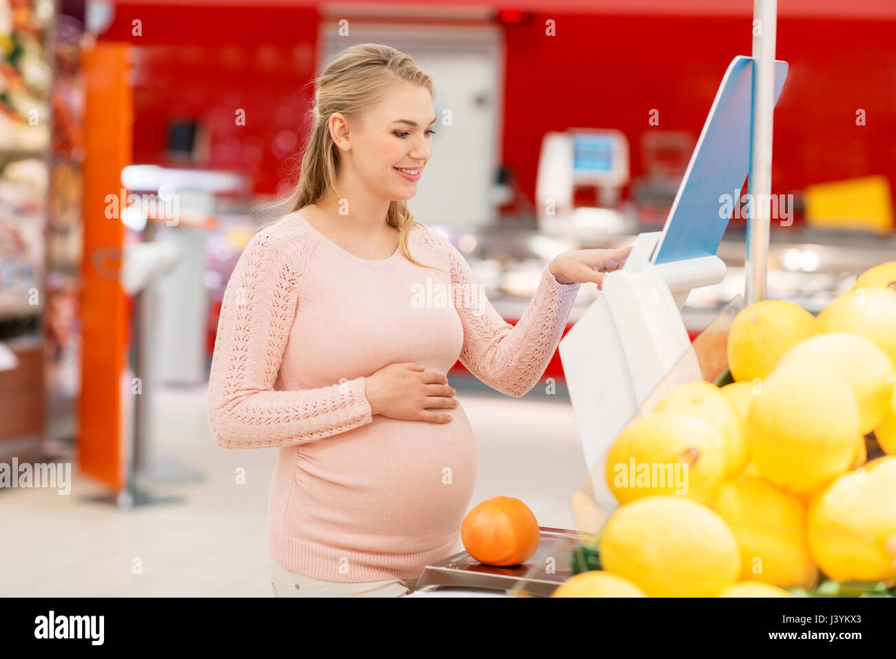 pregnant woman with grapefruit on scale at grocery Stock Photo Alamy
